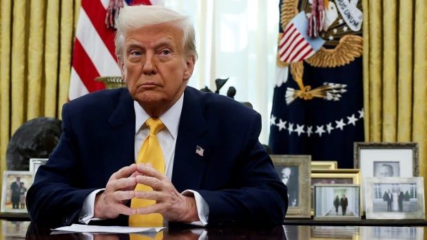 A man sits at a desk in the Oval Office.