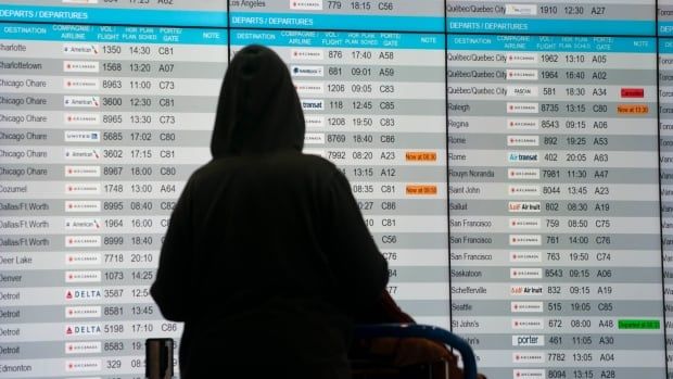 Woman checks the departure board at Pierre-Elliot Trudeau airport.