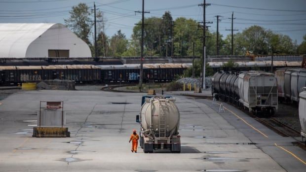 A worker walks next to a truck near a railyard.