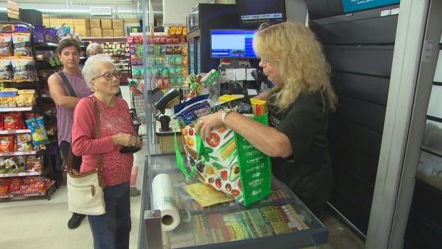 A cashier puts groceries into a reusable bag.