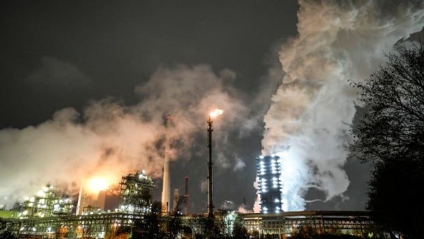 Industrial chimneys and white clouds of steam against a night sky