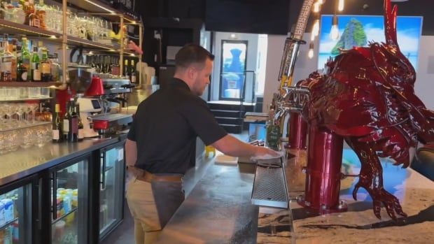 A man cleans the counter of a bar. 