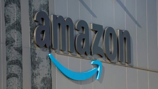 Large grey letters spell out "Amazon" on the side of a building, with a blue swoosh of an arrow underneath them, like a smile. 