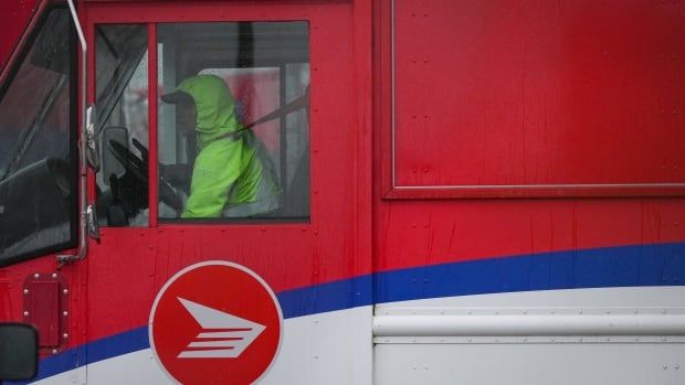 A Canada Post employee drives a mail truck at a delivery depot in Vancouver, B.C., Tuesday, Dec. 17, 2024. Canada Post trucks, conveyors and mail carriers are moving again after a month-long strike by more than 55,000 postal workers left letters and parcels in limbo. 