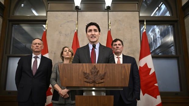 Trudeau and ministers stand behind a podium