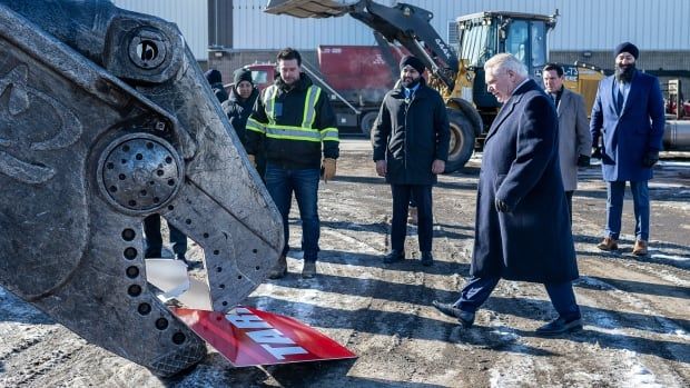 Ontario Progressive Conservative Leader Doug Ford looks on as an excavator destroys a sign reading 'Tariffs' during press conference at Triple M Metal in Brampton on Saturday February 1, 2025. THE CANADIAN PRESS/Eduardo Lima