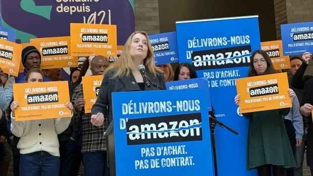 woman at podium surrounded by workers holding signs