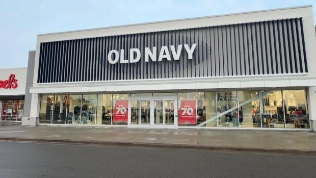 The outside of an old Navy retail store. Red sale signs hang in the window advertising up to 70% off.