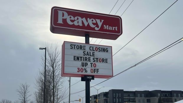 A tall red sign on a snow-covered street reads Peavey Mart. And below it on a rectangular white sign, 'Store closing sale. Entire store up to 30% off.'