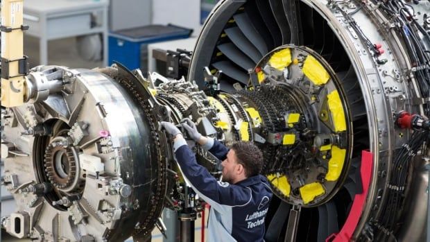 A man working on a large plane engine.