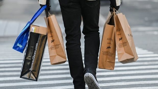 A person carries shopping bags along a street.