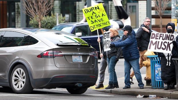 Protesters confront a vehicle on a city street. 