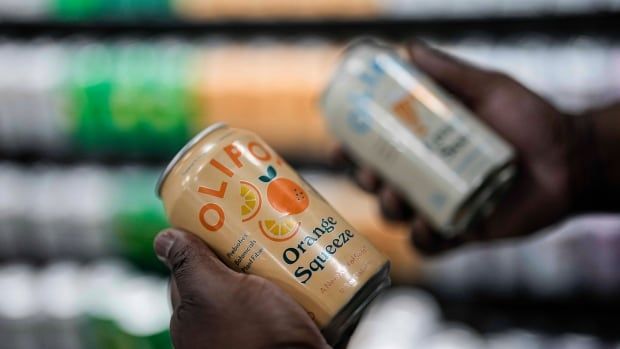 A person holds an orange soda can.