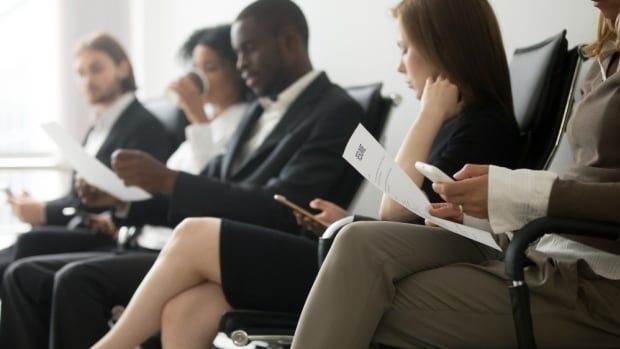 A group of people in business attire sit in a waiting room.