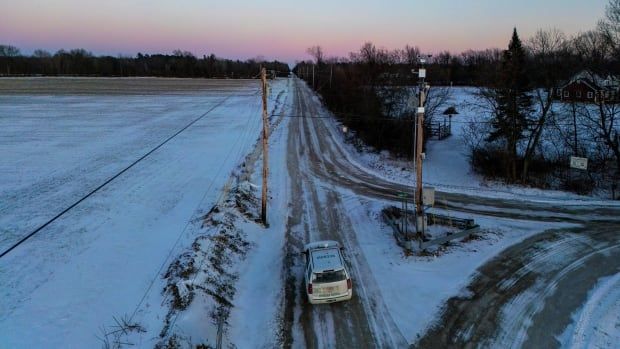 A single vehicle is seen from above on snowy country roads.