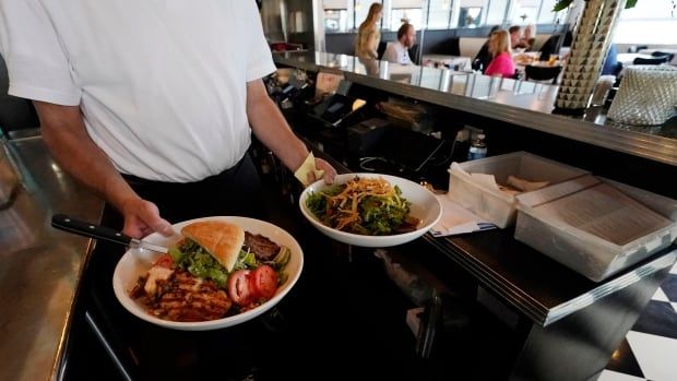 A person carries two plates in a  restaurant