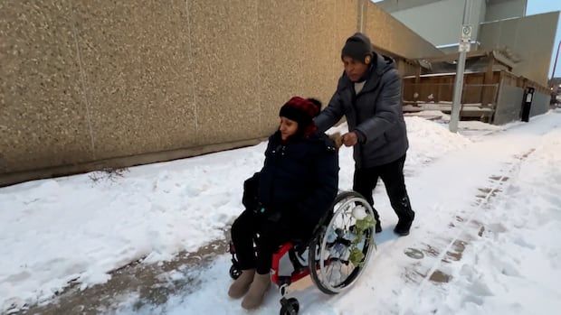 Woman in wheelchair on snow covered sidewalk