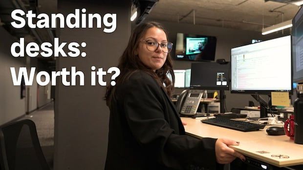 Reporter in front of standing desk. White writing on the left reads 'Standing desks: Worth it?'