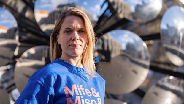 A woman wearing a blue sweatshirt with Mife&, Miso&, poses for a portrait in Montreal. 