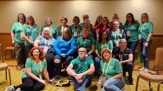 A group picture of people wearing the same green event t-shirts and lanyards. 