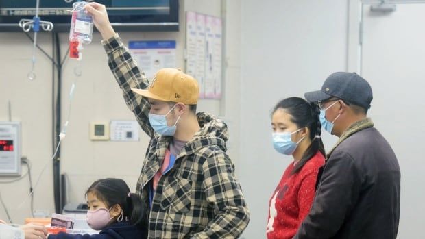 A family member holds an IV drip for a child receiving care at a hospital in China.