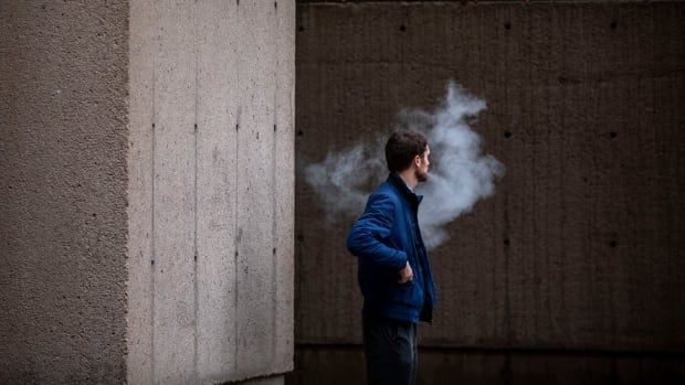 A man exhales vapor while using a vape pen in Vancouver.