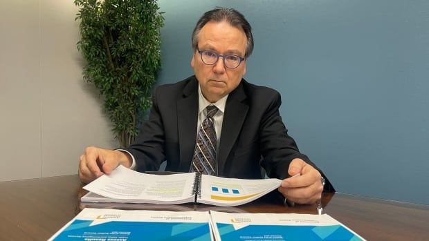 Alberta auditor general Doug Wylie poses with his office's November 2024 report which was released on Monday. 