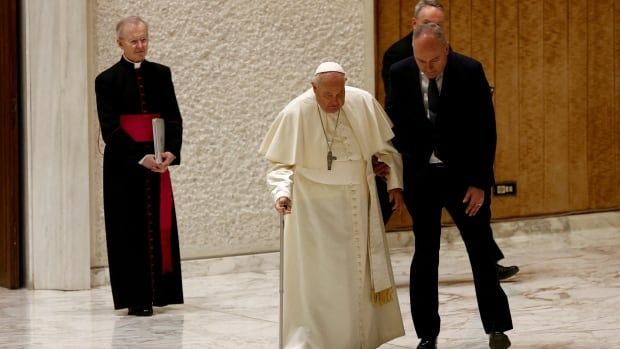 Pope Francis is assisted by his aide after a part of his cane broke off during his arrival to hold the Jubilee audience in Paul VI Hall at the Vatican on February 1, 2025. 