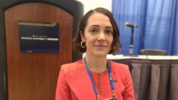 Woman with conference badge around neck and microphone in background