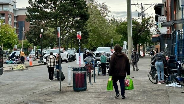 People walking and hanging out on a city street.