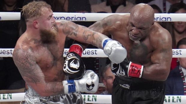 A man punches another man in a professional boxing ring.