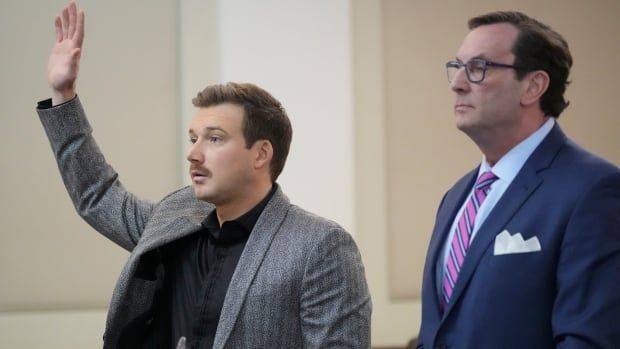 A man raises his hand in court.