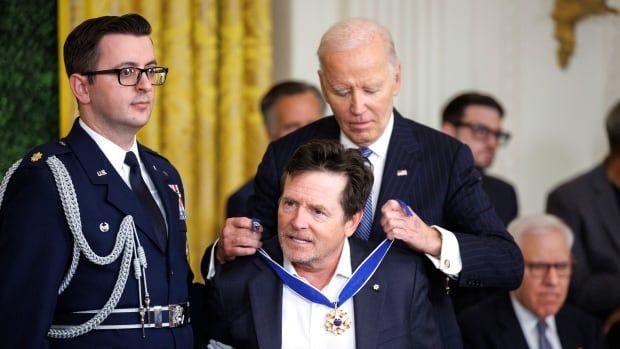 A person puts a medal around the neck of another person during a ceremony.