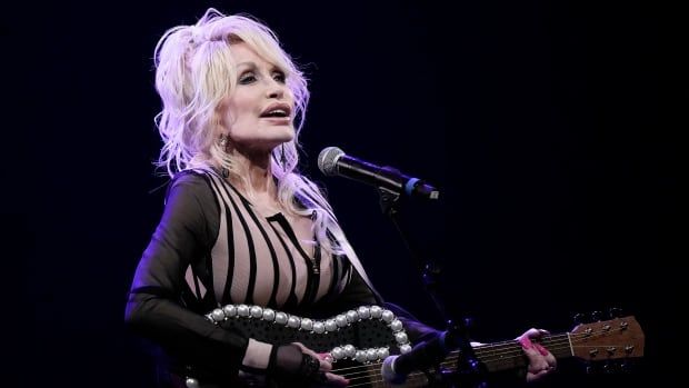 Dolly Parton performs with a guitar on stage.