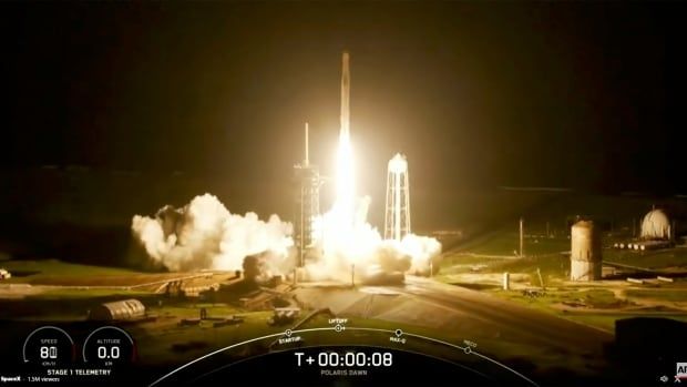 A rocket is shown leaving a platform in a darkened sky, lighting it up with smoke and fire.