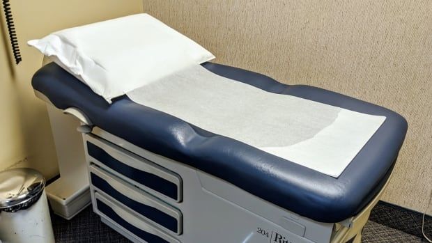 An empty medical exam bed is seen in a doctor's office.