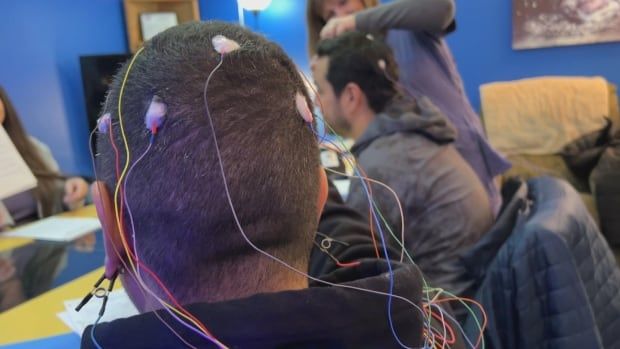 A man with electrodes attached to his head faces away from the camera.