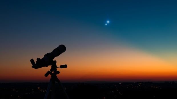 Silhouette of a astronomy telescope with twilight sky.