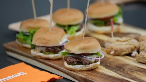 Burgers with skewers through them on a wooden board 