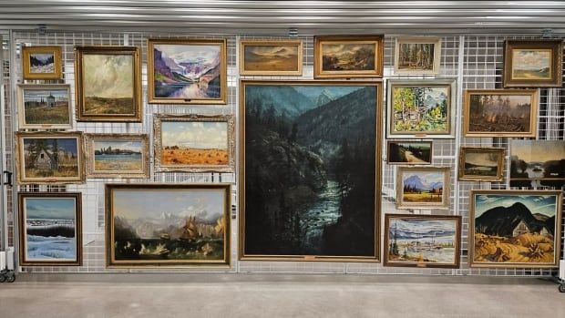 several paintings hang on large racks.