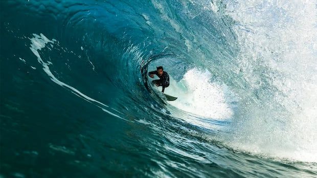 a surfer rides a deep tunnel