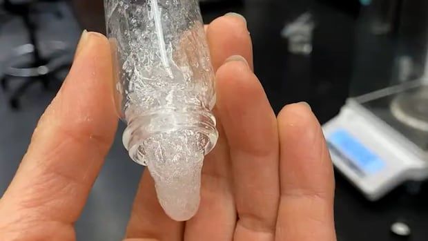 A clear slime pouring out of a small jar that is in a person's hand