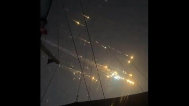 Streaks of light in the sky with silhouette of masts in the foreground.