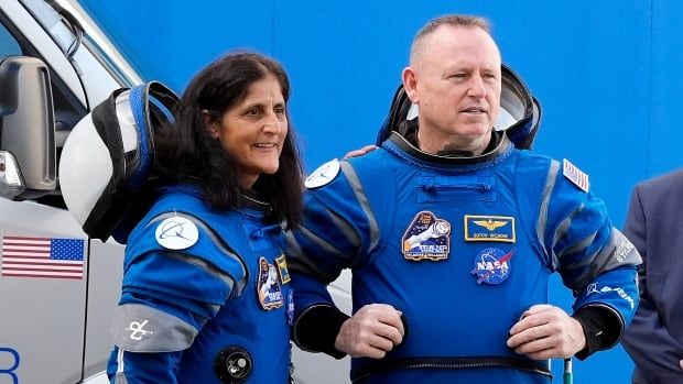 Two astronauts in blue space suits against a blue background.