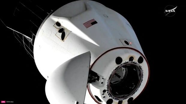 A white space capsule is shown against a black backdrop. There is a NASA logo in the corner. 