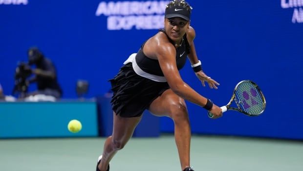 A female tennis player reaches to hit a ball across her body with the racket in her left hand.