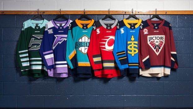 Six hockey jerseys are hung on the wall of a hockey dressing room.