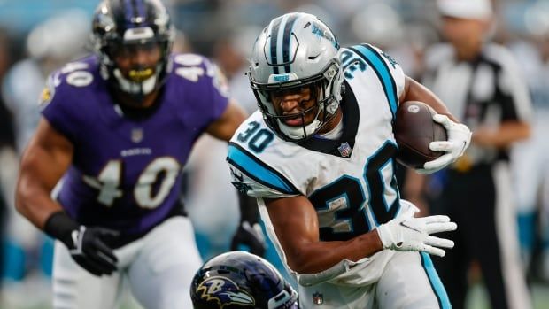 Carolina Panthers running back carries the football against the Baltimore Ravens in an NFL regular-season game.