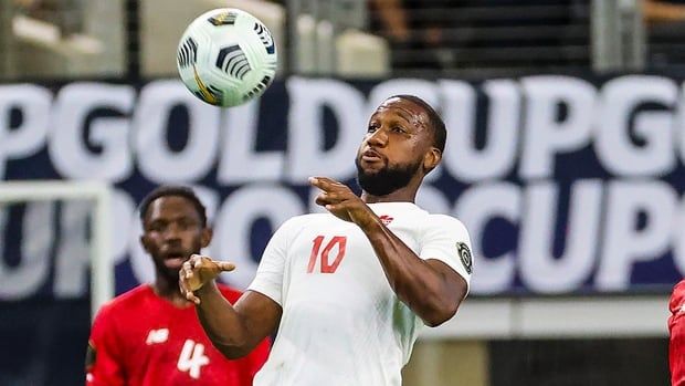 Two men's soccer players watch a ball in the air.