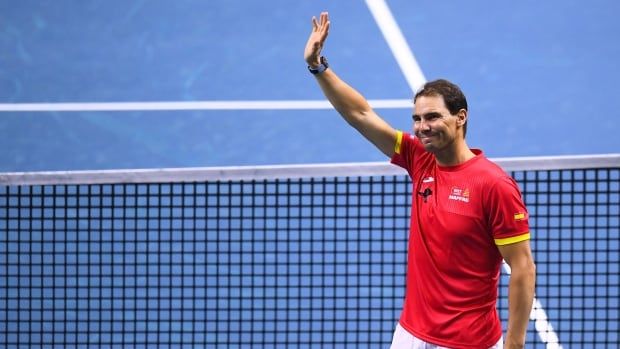 A men's tennis player waves to the crowd.